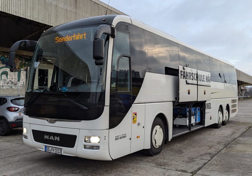 Bus steht mit offenen Gepäckklappen vor Halle